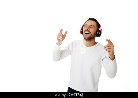 Handsome smiling young man dans les écouteurs pour écouter de la musique, danser et chanter isolé sur fond blanc. Banque D'Images