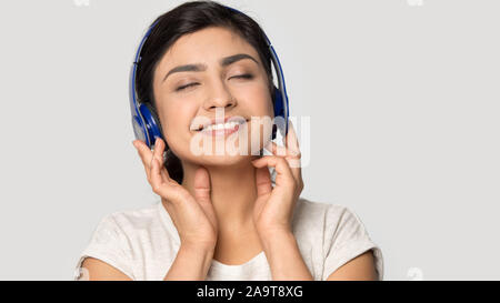 Sourire satisfait Indian girl in headphones appréciant la musique Banque D'Images