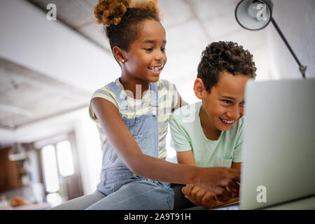 Jeu, étude, concept amusant. Des enfants heureux de passer du temps avec un ordinateur portable et la technologie moderne. Banque D'Images