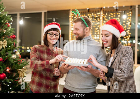 Professionnels d'affaires en prenant le dessert Santa caps détenus par leur collègue Banque D'Images