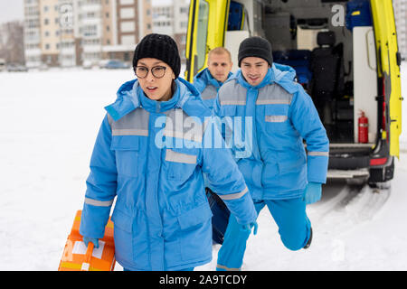 Groupe de jeunes paramédics en uniforme bleu pressé de malade en plein air Banque D'Images