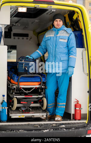 Jeune ambulancier avec trousse de premiers soins l'article en civière à l'intérieur voiture ambulance Banque D'Images