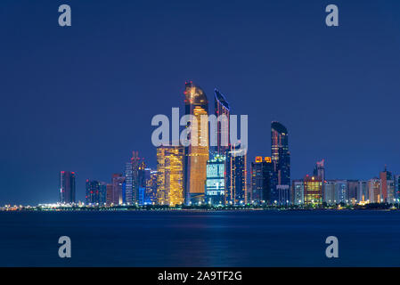 Abu Dhabi downtown skyline nuit reflète dans la mer, la capitale des Émirats arabes unis Banque D'Images