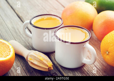 Deux tasses de jus d'orange, presse-agrumes et les agrumes. Banque D'Images