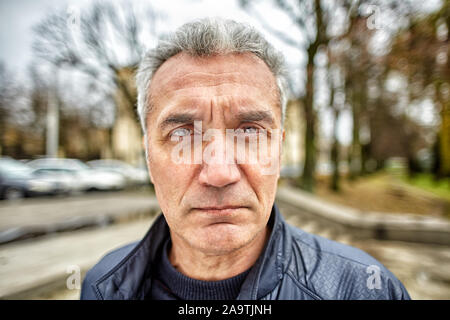 Un homme aux cheveux gris avec une coupe courte plus de 50 ans, est attentif en face de lui à l'extérieur, il ressemble à un employé de l'agence d'application de la loi Banque D'Images