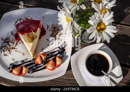 Gâteau au fromage classique avec la confiture de framboises sur une assiette décorée avec des fraises fraîches. Banque D'Images