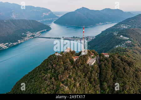 Drone aérien de sommet du Monte San Salvatore, Giorgio, et pont diga di melide en frontière italienne Banque D'Images