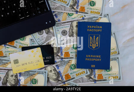 Une centaine de dollars de l'argent comme un ordinateur portable sur l'achat en ligne de billets avec l'aide de la carte de crédit sur le passeport de l'Ukraine Banque D'Images