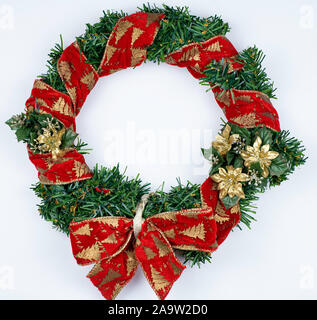 Couronne de Noël isolé sur fond blanc. Ruban Rouge sur vert pin artificiel et arc rouge, fleurs d'or. Banque D'Images