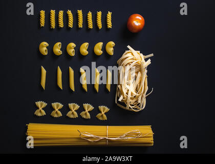 Différentes formes de pâtes et spaghettis sur fond noir. Banque D'Images