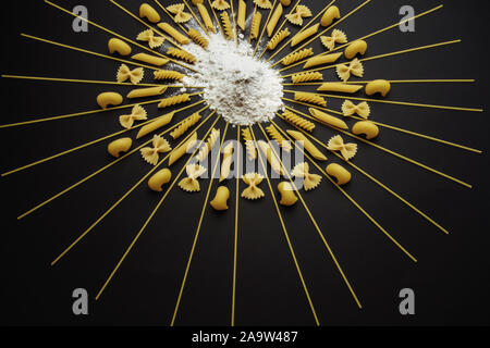 Organisé autour des pâtes de farine de blé et de pieux. Organisé géométrique différent type de pâtes sur fond noir. Banque D'Images