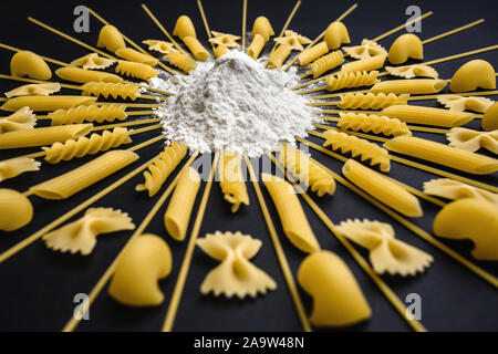 Organisé autour des pâtes de farine de blé et de pieux. Organisé géométrique différent type de pâtes sur fond noir. Banque D'Images
