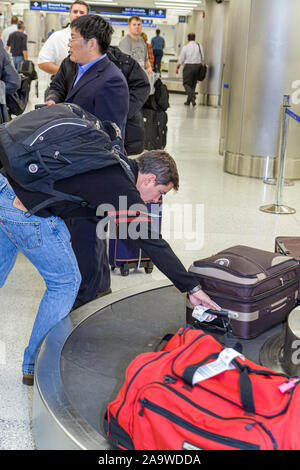 Aéroport international de Miami Florida MIA, arrivée de vol, zone de retrait des bagages, carrousel, bagages enregistrés, valise, homme asiatique hommes hommes, passagers ri Banque D'Images