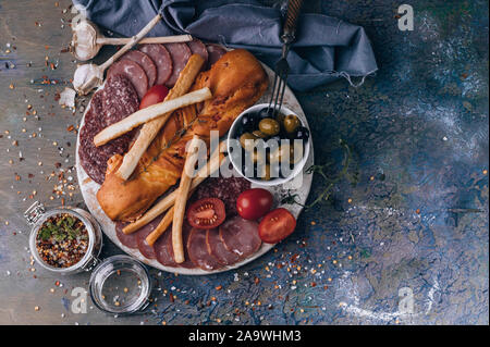 Vue de dessus d'un assortiment de viandes et de fromages sur une planche à découper ronde. Matières saucisse fumée, jambon, fromage, olives. Copy space Banque D'Images