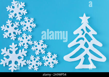Appliqué avec papier sculpté flocons blancs et l'arbre de Noël sur fond bleu. Carte postale de style minimaliste. Nouvelle année de mise en page à la main. Banque D'Images