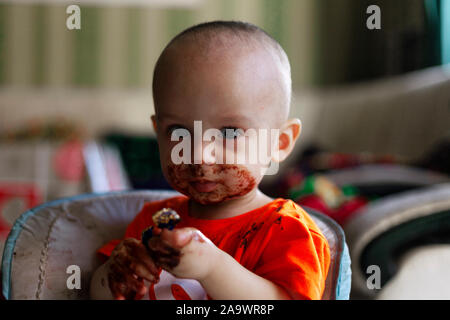 Petit enfant de manger du chocolat. Happy little boy enduite avec du chocolat autour de sa bouche. La mauvaise alimentation concept Banque D'Images