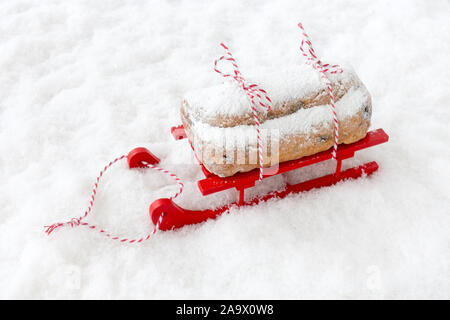 Dresdner stollen, un Allemand Christstollen, sur la neige en traîneau en bois rouge avec copie espace. High angle view. Banque D'Images