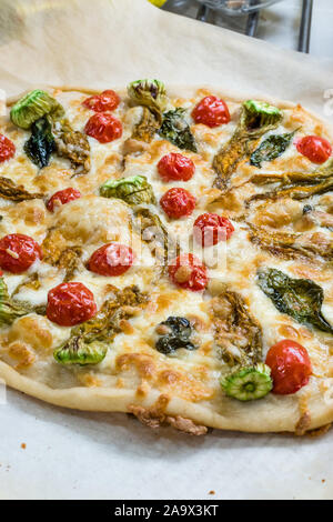 Du vrai Pizza italienne avec des fleurs de courgettes, les légumes et les tomates cerises. Aliments biologiques traditionnelles. Banque D'Images