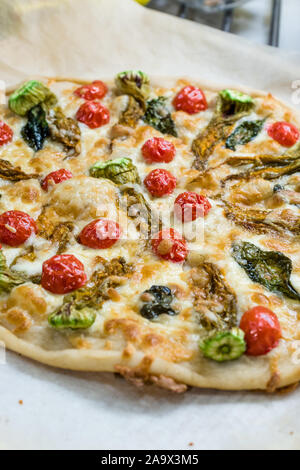 Du vrai Pizza italienne avec des fleurs de courgettes, les légumes et les tomates cerises. Aliments biologiques traditionnelles. Banque D'Images