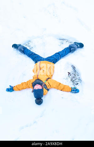 Petite fille dans la neige dessine un ange. Vue de dessus Banque D'Images