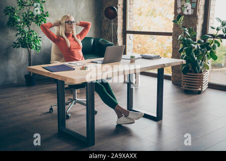 Photo pleine longueur de calme paisible propriétaire de l'entreprise positif femme procureur terminer le travail de démarrage de la table s'asseoir près de vous détendre avec les yeux dans les mains loft bureau Banque D'Images