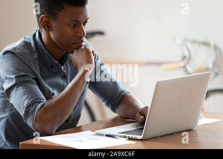 Mixed Race analyste d'affaires travaillant avec les statistiques de commercialisation. Banque D'Images