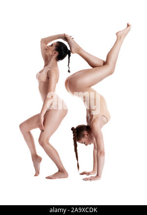 Deux gymnastes filles sportive avec des nattes, en beige justaucorps sont exécutant les exercices à l'aide du support et posant isolé sur fond blanc. Concept de Banque D'Images