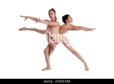 Deux gymnastes filles athlétiques avec des nattes, en beige justaucorps sont exécutant les exercices à l'aide du support et posant isolé sur fond blanc. Concept o Banque D'Images