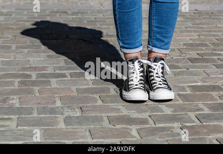 Chartres, France - 2 septembre 2019 : Droit de la partie inférieure de l'adolescent, les jambes en jeans et baskets Converse All Star dans une rue pavée. Banque D'Images