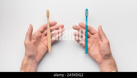 Les mains avec deux brosses à dent sur fond blanc Banque D'Images