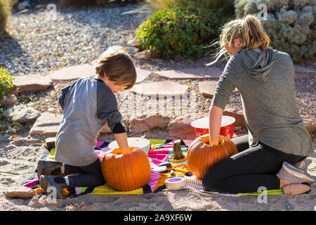 Une adolescente et son frère carving pumpkins à l'Halloween. Banque D'Images