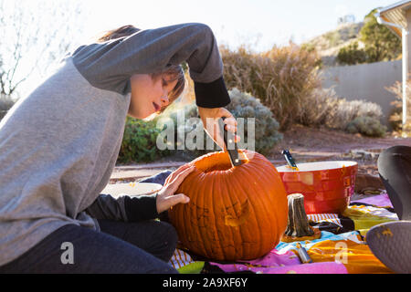 Un garçon de six ans, une sculpture de citrouille à l'Halloween. Banque D'Images