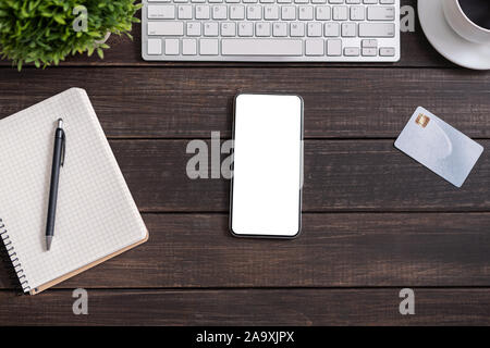 Smartphone moderne blanc avec écran vide sur la table de bureau en bois Banque D'Images