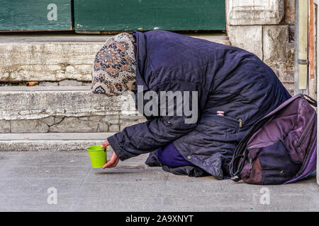 Venise, Italie unidentified mendiant dans la rue. Femme mendiant avec foulard, mendier de l'argent tenant une tasse à la voie piétonnière de Venise. Banque D'Images