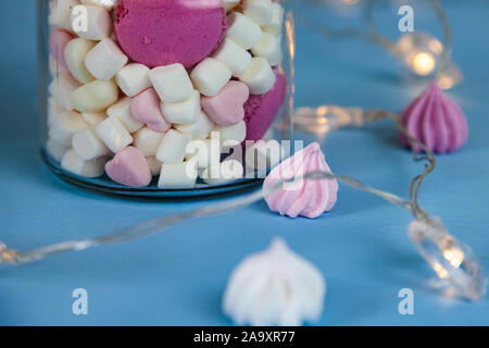 De la guimauve dans un bocal de verre et d'une guirlande de coeurs. Un délicieux dessert. Banque D'Images