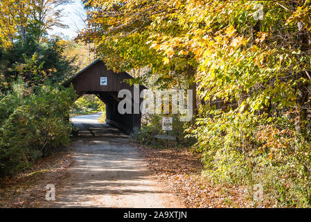 Vieux pont couvert de gravier le long d'une route de campagne bordée d'arbres d'automne colorés sur une journée ensoleillée Banque D'Images