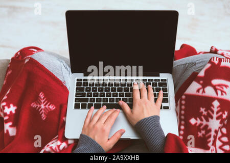 Femme couverts par l'aide d'un ordinateur portable avec plaid rouge écran noir Banque D'Images