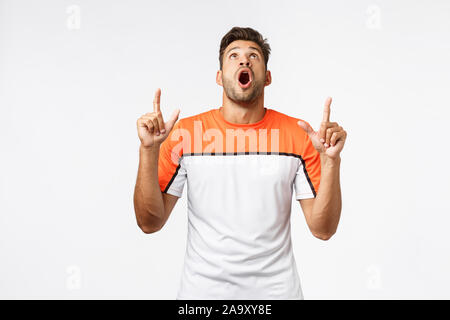 Guy drop jaw de stupéfaction, superbe grand produit au-dessus de la publicité. Bel homme masculin en vêtements d'élever la tête, haletant et se demande Banque D'Images