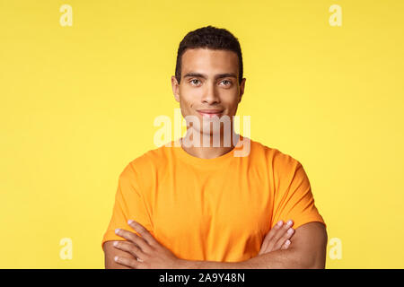 Studio shot smiling, joyeux et fort jeune athlète mâle en t-shirt, cross arms poitrine sûr de lui, sûr de poser, en souriant Banque D'Images