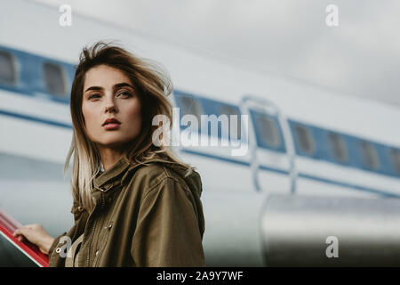 Portrait de belle jeune femme debout sur la rampe d'accès à l'encontre de l'avion. Banque D'Images