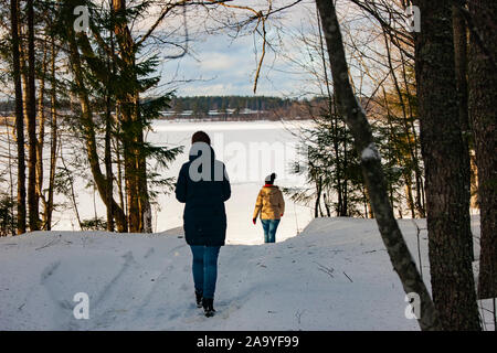 Deux jeunes filles à pied à travers la forêt d'hiver à un lac gelé. Un merveilleux changement de saison, l'arrivée du printemps, tout vient à la vie avec la FIRS Banque D'Images