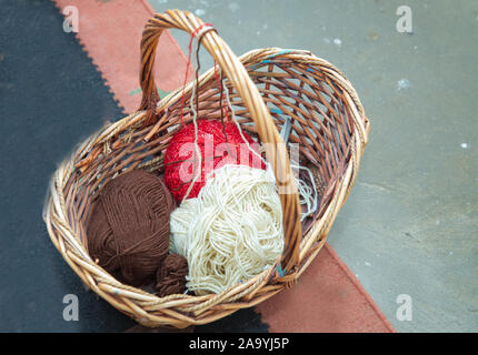 Pour définir l'observation et l'aiguille. balle de laine et des aiguilles à tricoter dans panier . Dimensions brown panier avec une poignée de balles de laine et tricot. Banque D'Images