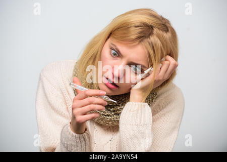 Mesurer la température. La fièvre de la pause des recours. La prise de température et d'évaluer les symptômes. Concept à haute température. Femme se sent gravement malade l'éternuement. Fille en tissu écharpe tenir thermomètre et close up. Banque D'Images