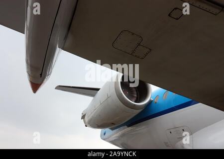 Vue de dessous l'aile d'un gros avion blanc et bleu avec moteur à réaction Banque D'Images
