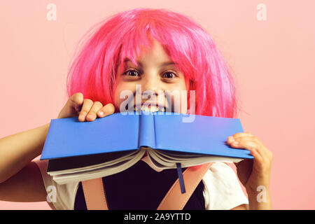 Fille de l'école avec des professionnels de la vue isolé sur fond rose. Élève de l'uniforme scolaire avec perruque rose. Retour à l'école et l'éducation concept. Fille de moustiques gros livre bleu. Banque D'Images