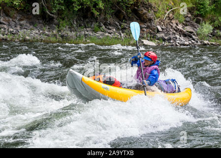 Woman paddling un kayak gonflable sur la rivière Grande Ronde de l'Oregon. Banque D'Images