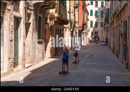 Enfants jouant sur les scooters, Calle dei Furlani, Castello, Venise, Italie : une région bien loin de l'drags Banque D'Images