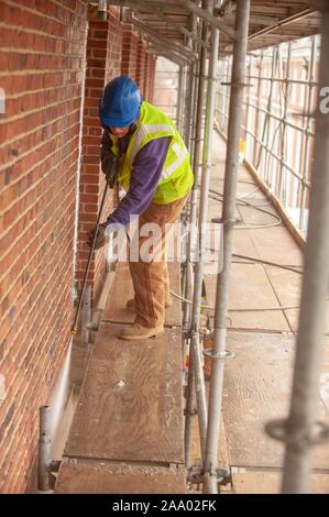 Une personne portant l'équipement de sécurité et debout sur un échafaudage, utilise un pistolet tout en travaillant à l'extérieur de Gilman Hall, lors d'une journée froide à la Johns Hopkins University, Baltimore, Maryland, le 11 mars 2009. À partir de la collection photographique de Homewood. () Banque D'Images