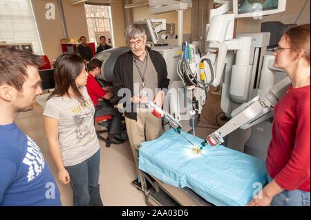 Russell Taylor, professeur d'informatique, discute avec des étudiants en génie de l'École de merlan tandis qu'un bras de robot chirurgical da Vinci travaille dans une fausse salle d'opération, à l'Université Johns Hopkins University, Baltimore, Maryland, le 6 avril 2009. À partir de la collection photographique de Homewood. () Banque D'Images