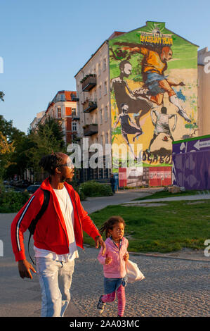 Père noir avec sa fille et une maison près de Le Mauerpark Berlin, lumière du soir en Allemagne. Wellcome à Belin, équipe brésilienne. Joga Bonito. Mauerp Banque D'Images